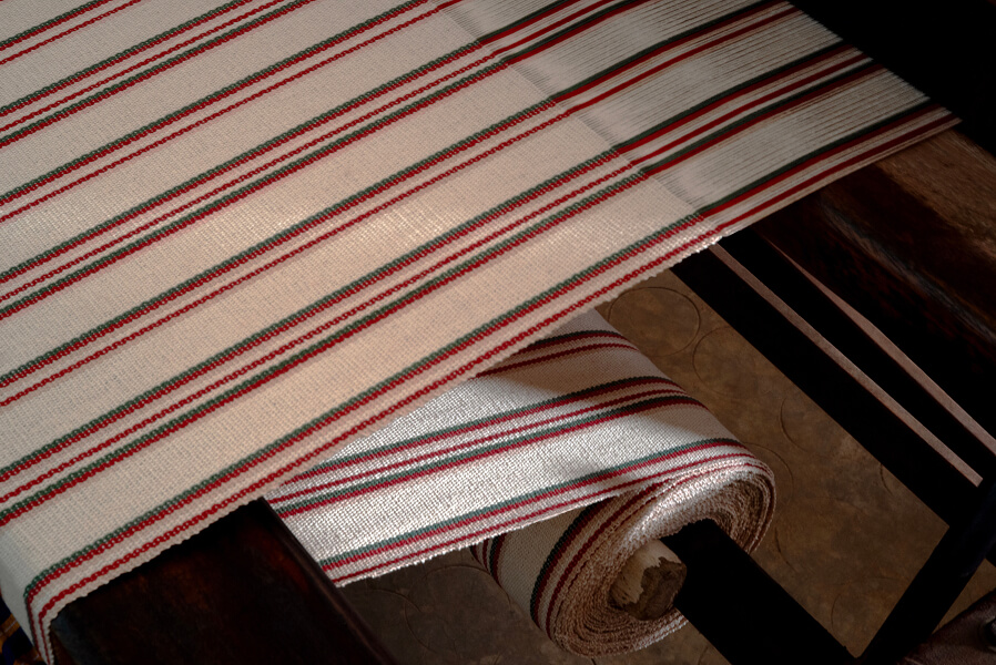 Individual threads merge into a finished textile, defined by a dense and distinct grain.