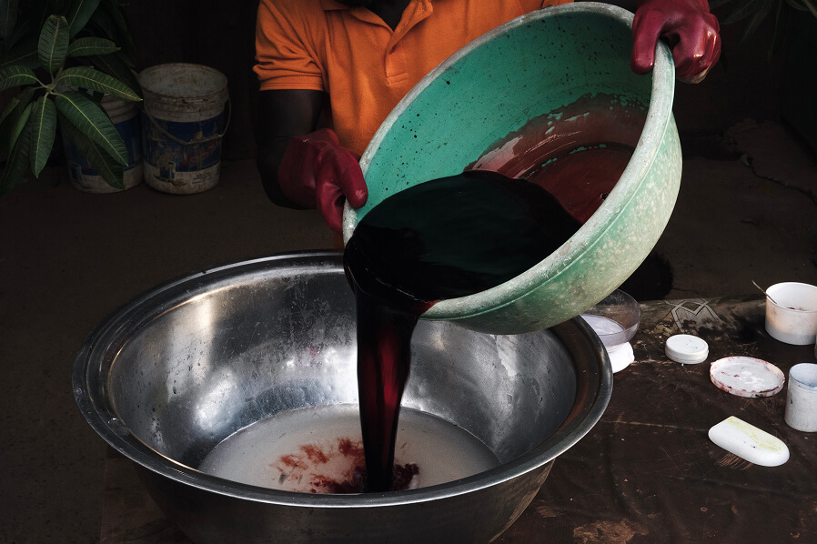 The introduction of pigment through manual immersion, a process of gradual absorption.